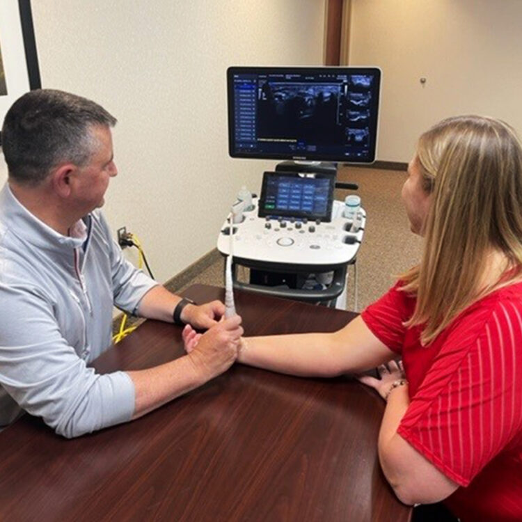 Dr. Perry scanning female patients wrist with probe to show the carpal tunnel and key anatomy with ultrasound. 